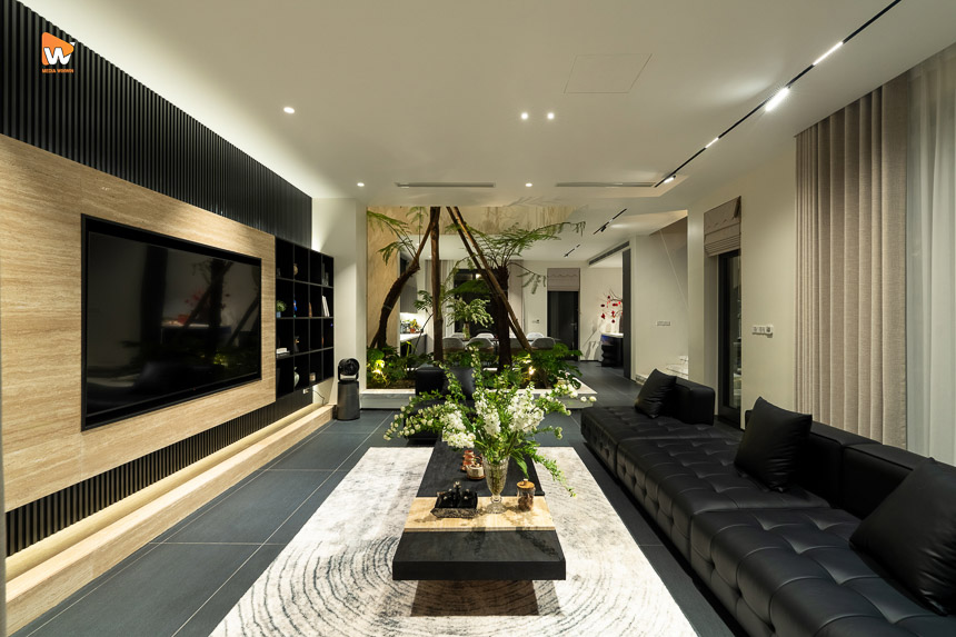 Phòng khách tông tối với tường ốp gỗ và sofa da đen trong nhà ở Hoài Đức - Media WinWin